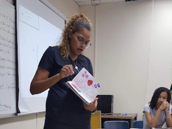 student presenting in front of class holding a notebook