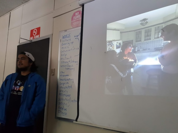 student presnting in front of class standing by a whiteboard