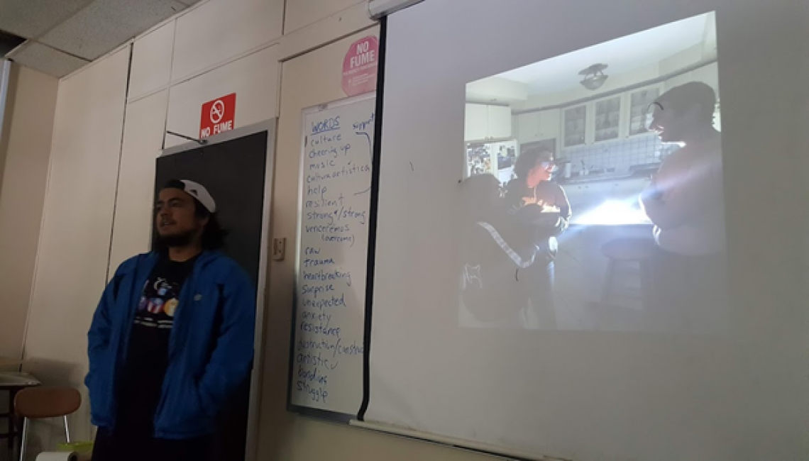 student presnting in front of class standing by a whiteboard